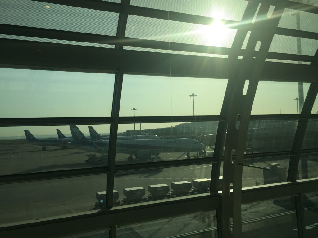 早朝の羽田空港第2ターミナルから見た朝日とANA機