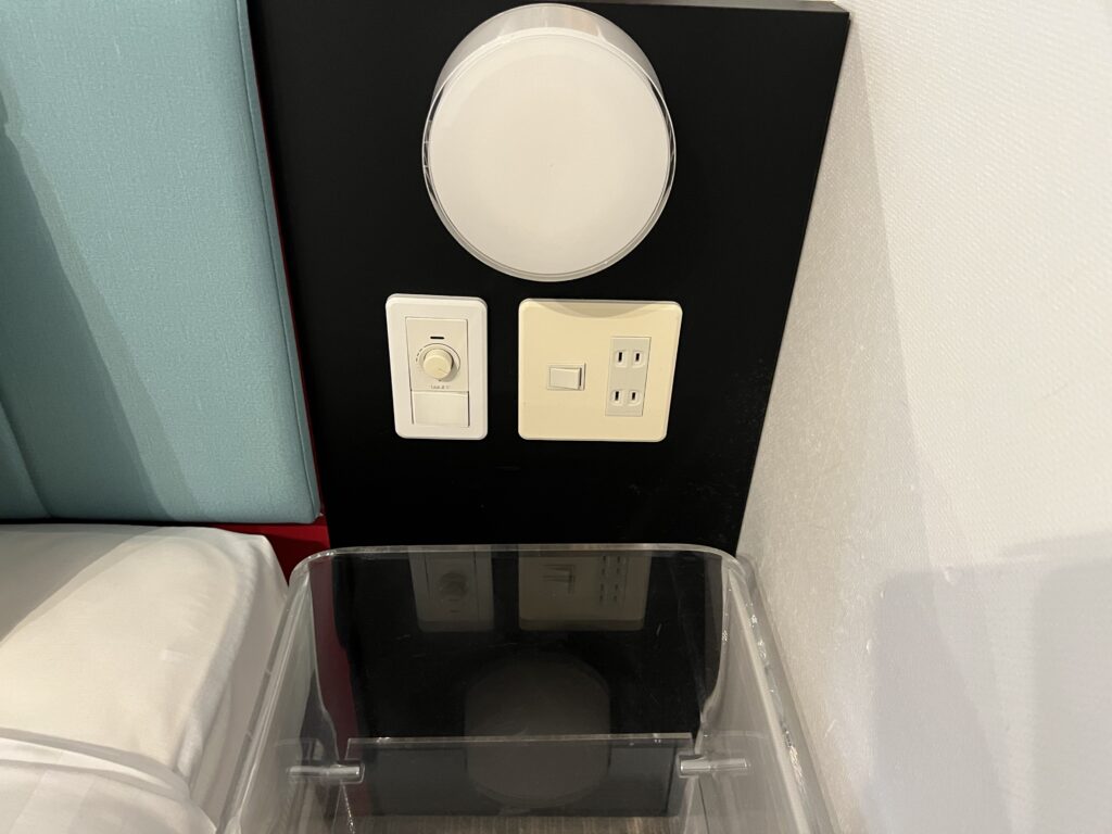 クイーンベッド横にある照明スイッチとコンセント